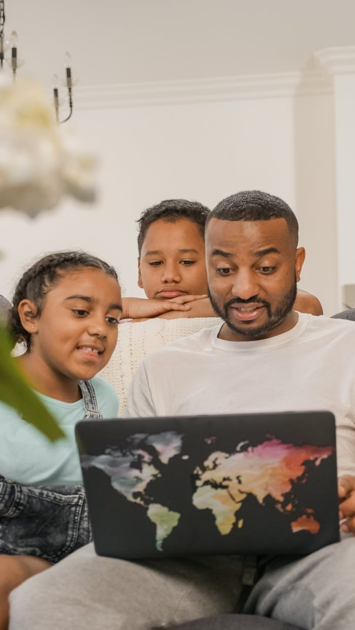 Father bonding with kids using a laptop in a cozy living room setting.